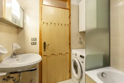 a bathroom with a sink and a washing machine at Col Rodella - Canazei in Canazei