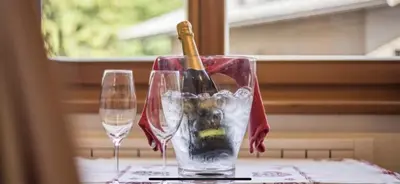 a bottle of wine in a glass on a table with two glasses at Villa Anita San Vigilio di Marebbe in San Vigilio Di Marebbe