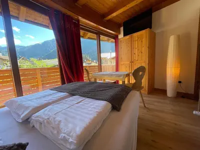 a bedroom with a bed and a large window at Villa Anita San Vigilio di Marebbe in San Vigilio Di Marebbe