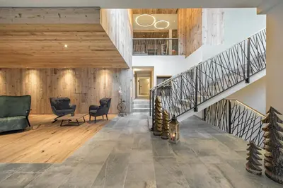 a lobby with a staircase and two chairs and tables at Hotel Torgglerhof in Bressanone