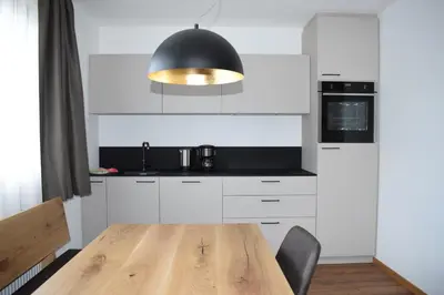 a kitchen with a wooden table and a black light fixture at Pension Hofer in Brunico