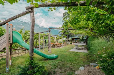 a playground with a green slide in a yard at Residence Haus Kalterersee in Caldaro