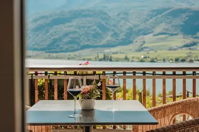 two glasses of wine on a table on a balcony at Residence Haus Kalterersee in Caldaro