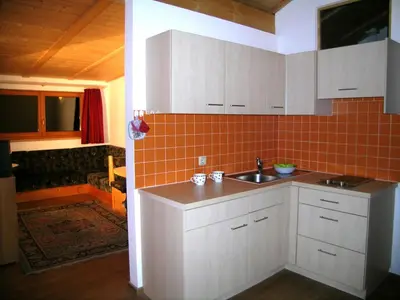 a kitchen with white cabinets and an orange tile wall at Residencesora in San Vigilio Di Marebbe
