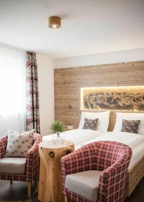 a bedroom with a bed and two chairs at Hotel Chalet Dolomites in Alpe di Siusi