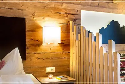 a bedroom with a wooden wall with a bed and a lamp at Hotel Chalet Dolomites in Alpe di Siusi