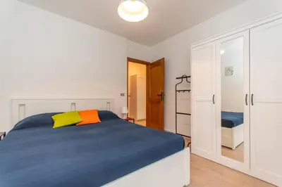 a white bedroom with a blue bed and a closet at Condominio al Lago in Alleghe