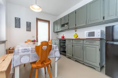 a kitchen with green cabinets and a table and a refrigerator at Condominio al Lago in Alleghe