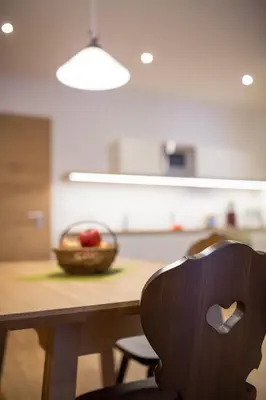 a wooden table with a bowl of fruit and a wooden chair at Residence Grünwald in San Martino