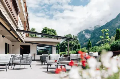 a patio with chairs and tables with mountains in the background at Hotel Jager Hans in San Martino