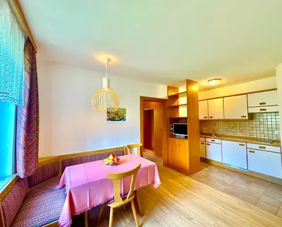 a kitchen with a table with a pink table cloth at Appartement Hortensia - Haus Midi in Marlengo