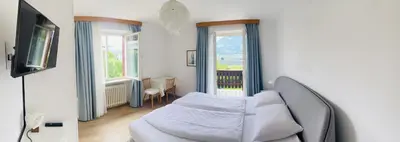 a bedroom with a bed and a couch and windows at Appartement Hortensia - Haus Midi in Marlengo