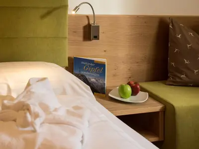 a bed with a book and two apples on a table at Appartement Garden in Valdaora