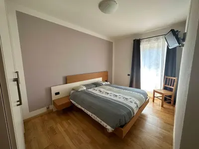 a bedroom with a bed and a chair and a window at Pippi Home in Castello di Fiemme