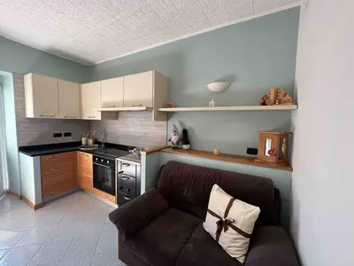 a living room with a couch and a kitchen at Pippi Home in Castello di Fiemme