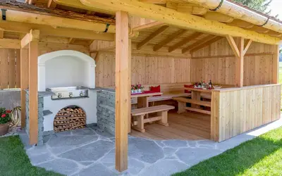 a wooden pavilion with a table and a fireplace at Appartements Steiner in Valdaora
