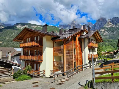 a house with wooden balconies on a mountain at Alessio House in Pozza di Fassa