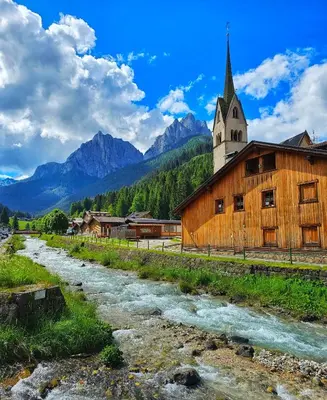 a church and a river in front of a building at Alessio House in Pozza di Fassa