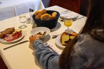 a woman sitting at a table with a plate of food at Aparthotel Zum Schlössl in Villa Ottone