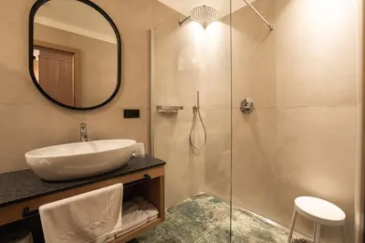 a bathroom with a sink and a shower with a mirror at Aparthotel Zum Schlössl in Villa Ottone