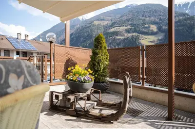 a balcony with a chair and a pot of flowers at Aparthotel Zum Schlössl in Villa Ottone