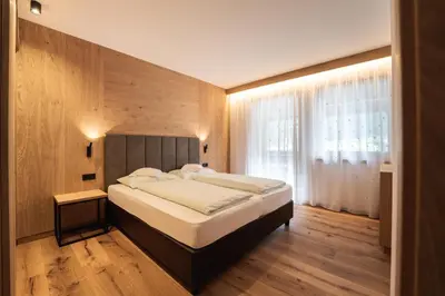 a bedroom with a bed and a large window at Aparthotel Zum Schlössl in Villa Ottone