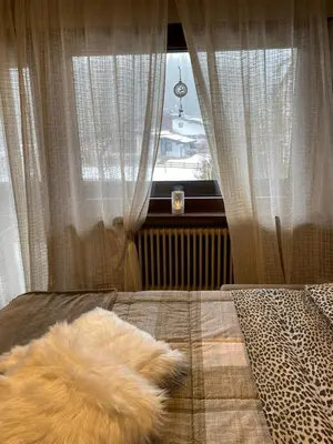 a pile of fur laying on a bed next to a window at Case Vacanza Marco - Junior Suite 116 in San Martino di Castrozza