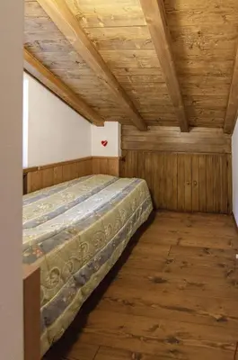 a bedroom with a bed in a room with wooden ceilings at Estate in montagna in San Vito di Cadore
