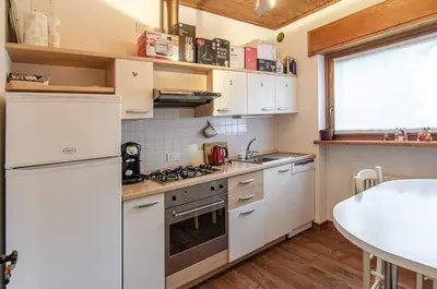 a kitchen with white appliances and a table at Estate in montagna in San Vito di Cadore
