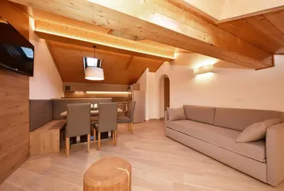 a living room with a blue couch and a chair at Appartamenti Maria in Canazei