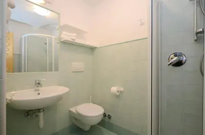 a white bathroom with a sink and a shower at Appartamenti Maria in Canazei