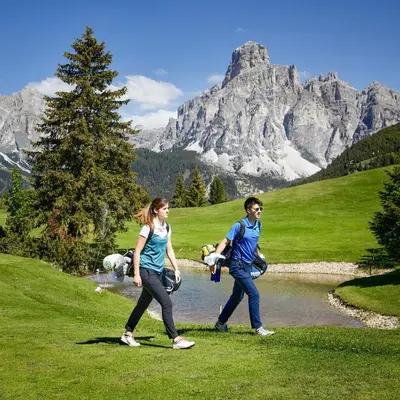a man and a woman walking along a river in the mountains at Apartments Brunella in La Villa