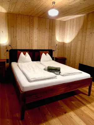 a large bed in a room with wooden walls at Schallerhof Sterzing - Deine Auszeit mit Ausblick in unseren Ferienwohnungen auf dem Bergbauernhof in Südtirol in Vipiteno