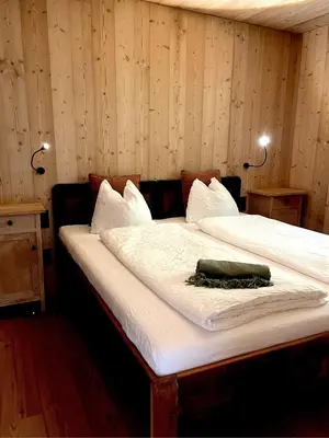a large bed in a room with two lights at Schallerhof Sterzing - Deine Auszeit mit Ausblick in unseren Ferienwohnungen auf dem Bergbauernhof in Südtirol in Vipiteno