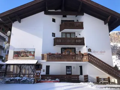 a building with stairs on the side of it in the snow at Appartamento dles Dolomites in Corvara in Badia