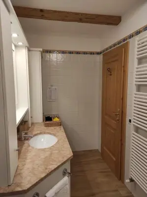 a bathroom with a white sink and a door at Appartamento dles Dolomites in Corvara in Badia