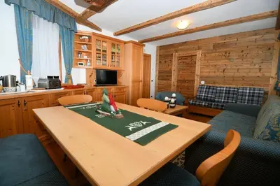 a dining room with a wooden table and chairs at Appartamento dles Dolomites in Corvara in Badia
