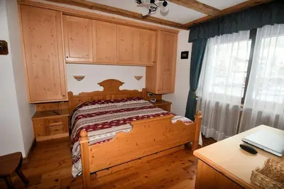 a bedroom with a wooden bed and a desk at Appartamento dles Dolomites in Corvara in Badia