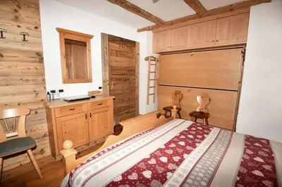 a bedroom with a bed and a wooden wall at Appartamento dles Dolomites in Corvara in Badia