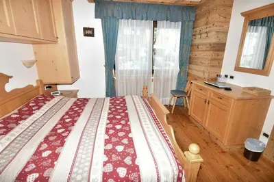 a bedroom with a bed and a desk and a window at Appartamento dles Dolomites in Corvara in Badia