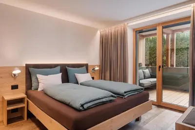 a bedroom with a bed and a balcony at Max Green Wood Apartments in Siusi