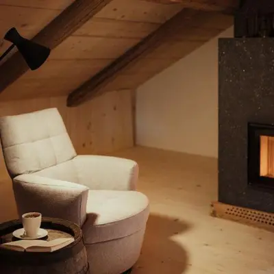 a living room with a chair and a fireplace at Ostí Vedl in San Martino in Badia