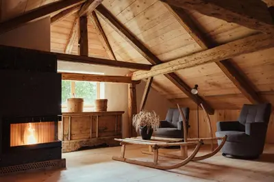 a living room with a fireplace and two chairs and a table at Ostí Vedl in San Martino in Badia