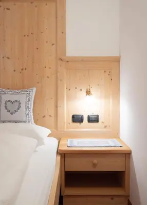 a bedroom with a bed and a wooden wall at Apartments Mauriz in Selva di Val Gardena