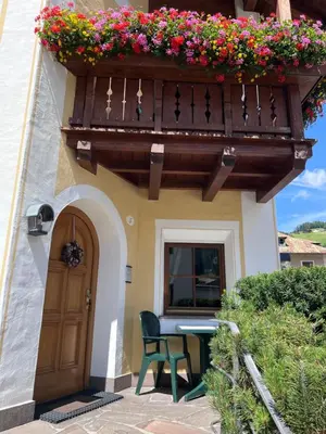 a house with a balcony with a table and a balcony at Apartments Mauriz in Selva di Val Gardena