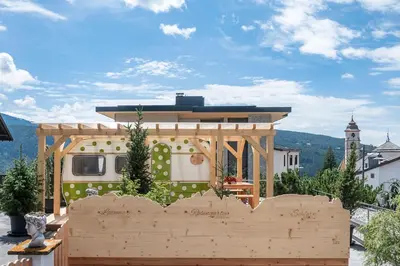 a food truck parked on a balcony with a wooden fence at Mountain Caravan - Zirben Nestl in Nova Ponente