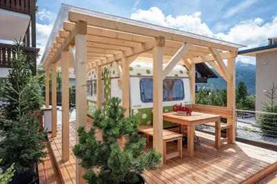 awning and table on a deck with an rv at Mountain Caravan - Zirben Nestl in Nova Ponente