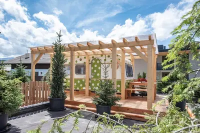 a wooden pergola with a wooden table on a deck at Mountain Caravan - Zirben Nestl in Nova Ponente