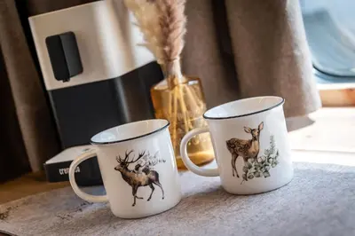 two coffee mugs with deer on them sitting on a table at Mountain Caravan - Zirben Nestl in Nova Ponente
