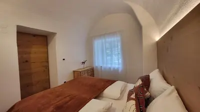 a bedroom with a wooden bed and a window at Fruemess - Historic Refugium in Parcines